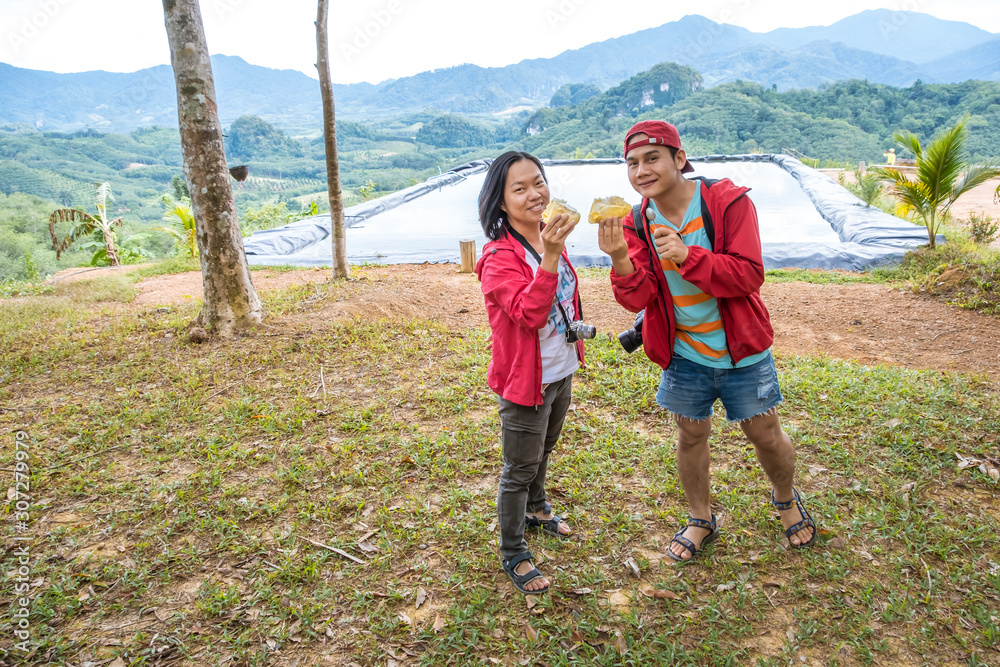 Asian tourist holding durian king of fruits. Durians have a lot of fiber, Polyphenols and antioxidants. Good for health and very delicious. Food or fruit concept. Asian tourist holding durian king of fruits. Durians have a lot of fiber, Polyphenols and antioxidants. Good for health and very delicious. Food or fruit concept.