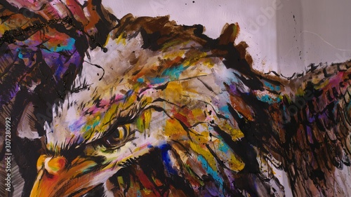 Artist designer draws an eagle on the wall. Craftsman decorator paints a picture with acrylic oil color. Painter painter dressed in a paint coat. Indoor. Dark magic cinematic look.