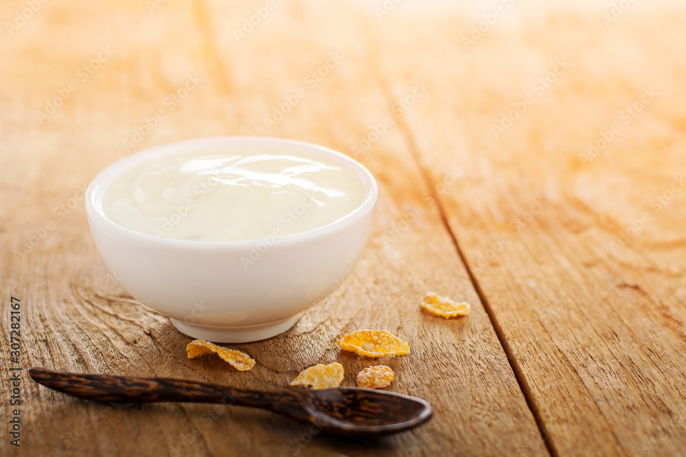 Yogurt in a white cup placed on a wooden table And the morning light shining down Yogurt in a white cup placed on a wooden table And the morning light shining down