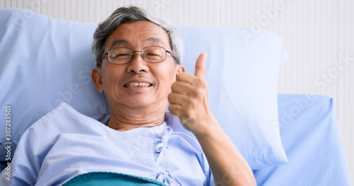 Male patient smiling and lying down on sickbed in hospital room.