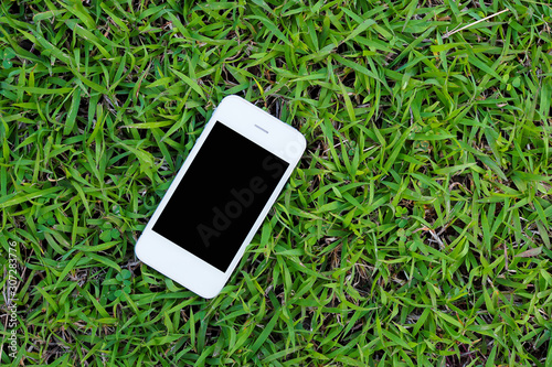 Mobile smart phones on green grass background. top view