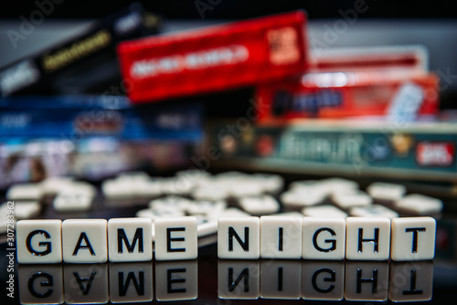Game Night spelled out in letter tiles on black background with boardgames in the background