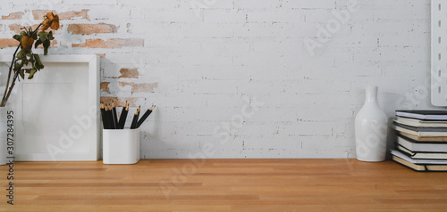 Cropped shot of comfortable workplace with mock up frame, office supplies and copy space on wooden table