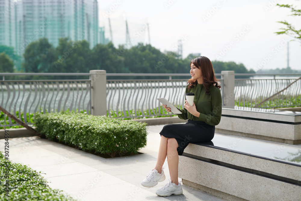 Pretty young woman with beautiful smile using tablet in the park Pretty young woman with beautiful smile using tablet in the park