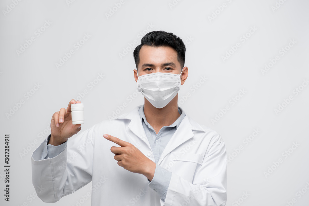 Handsome Male Doctor holding empty white or blank Pills bottle. standing isolated over white background