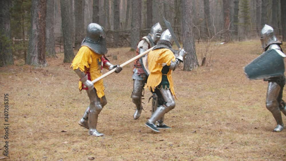 Four men knightes having a training fight on the field in the middle of the forest - recreation of old times Four men knightes having a training fight on the field in the middle of the forest - recreation of old times