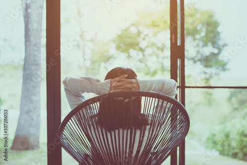 Woman sitting with hands on her head on modern chair in bedroom,Relaxing time,Back view #307286133