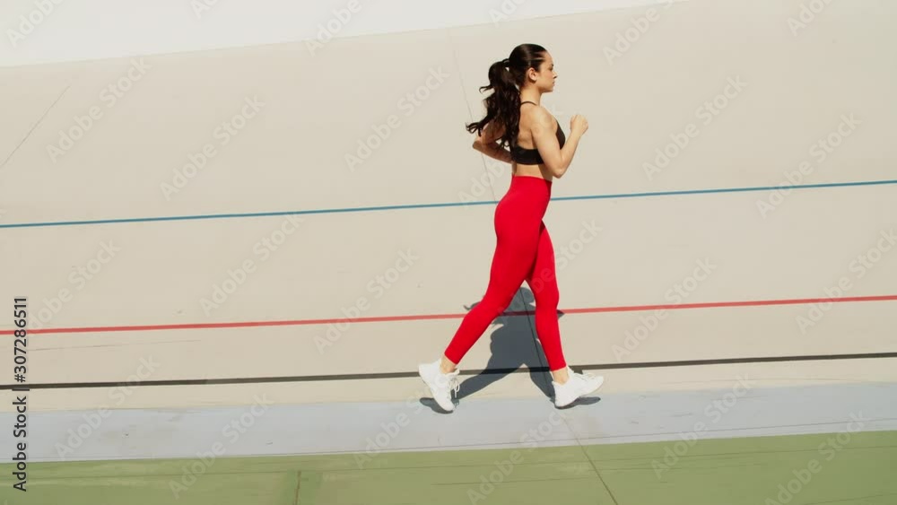 Fit woman jogging on stadium track. Woman runner running in slow motion Fit woman jogging on stadium track. Woman runner running in slow motion