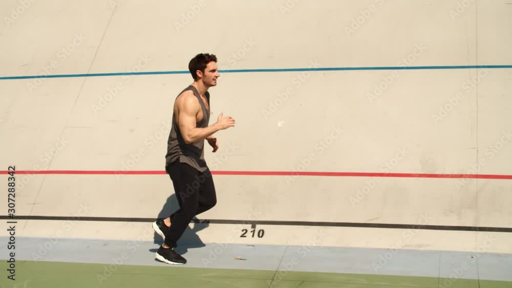 Athletic runner man running on athletics track. Fit man jogging on sport track Athletic runner man running on athletics track. Fit man jogging on sport track
