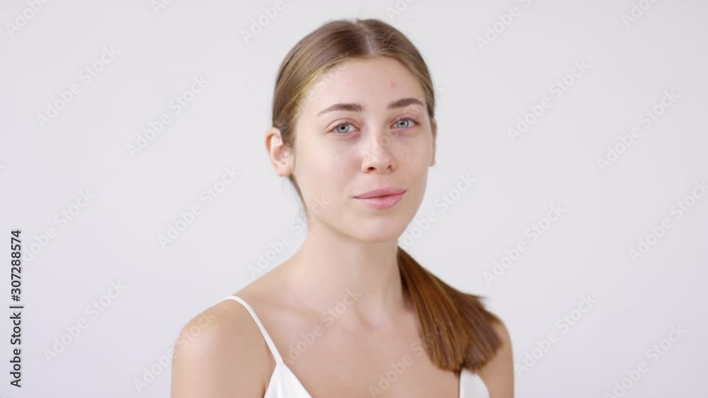 Portrait shot of beautiful young woman with no makeup on standing isolated on grey background and posing for camera Portrait shot of beautiful young woman with no makeup on standing isolated on grey background and posing for camera