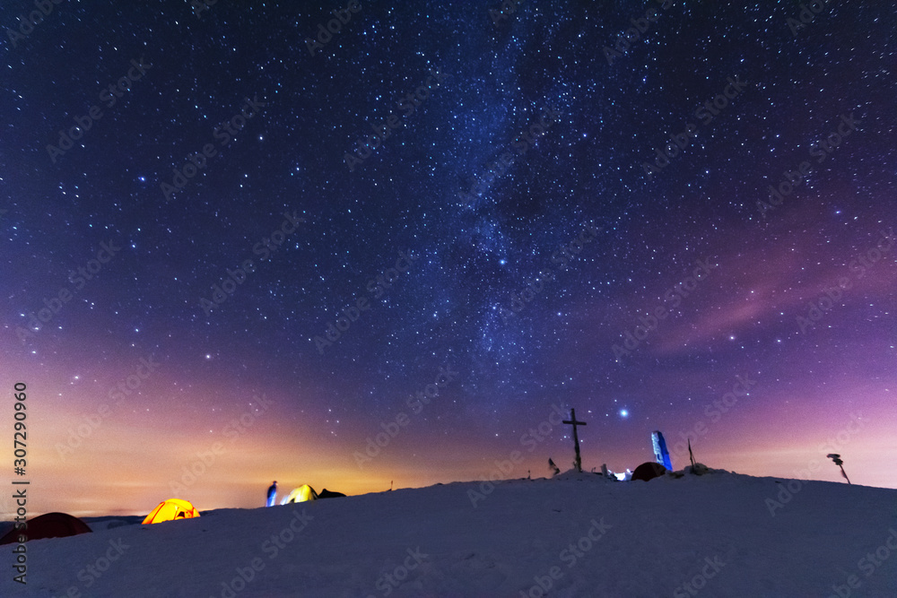 Great bright campsite with colorful tourist tents, on top in the Ukrainian Carpathian Mountains, at night with views of the stars and the Milky Way	