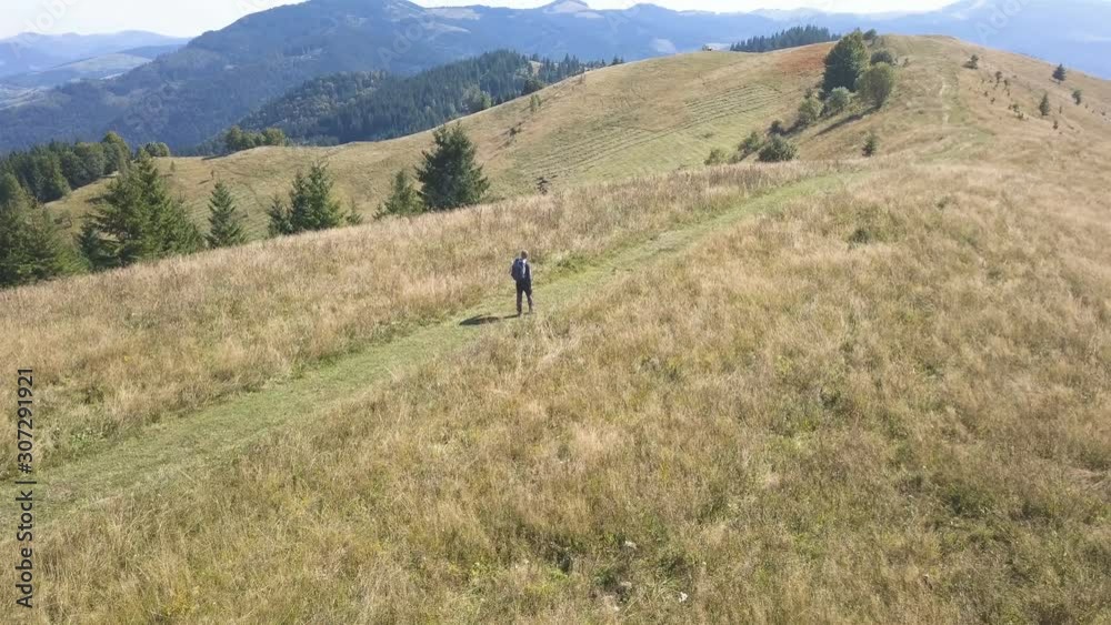 4K Aerial. Man backpacker tourist go away on ridge in autumn mountain hill. 4K Aerial. Man backpacker tourist go away on ridge in autumn mountain hill.