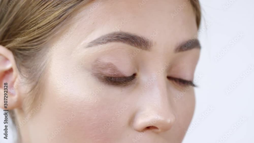 Extreme close up shot with timelapse of young woman using makeup brush and putting brown eyeshadow on her eyelid, then blending it Extreme close up shot with timelapse of young woman using makeup brush and putting brown eyeshadow on her eyelid, then blending it