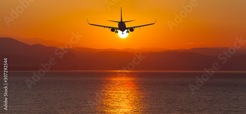 Airplane flying to the sunset over the sea-