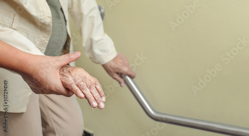 Elderly woman holding on handrail with caregiver