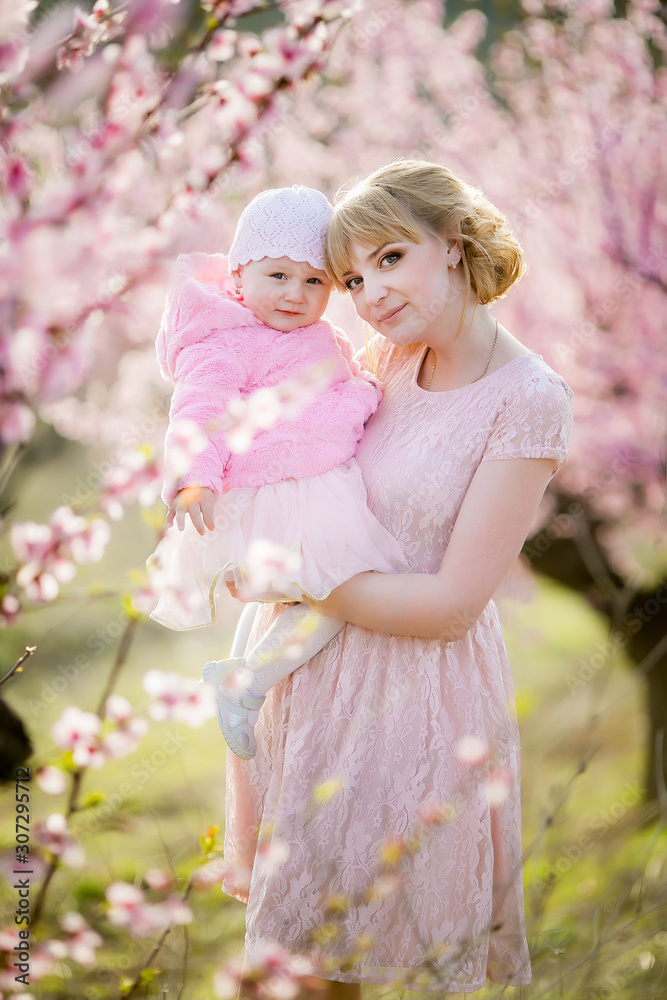 Mom and a girl in pink dresses walk and have fun in a natural garden in spring. Mom and a girl in pink dresses walk and have fun in a natural garden in spring.