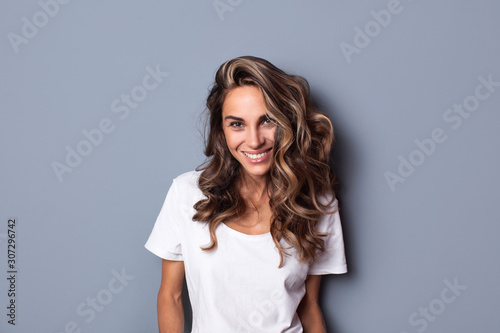 Portrait of young beautiful smiling cute girl looking at camera over grey background.