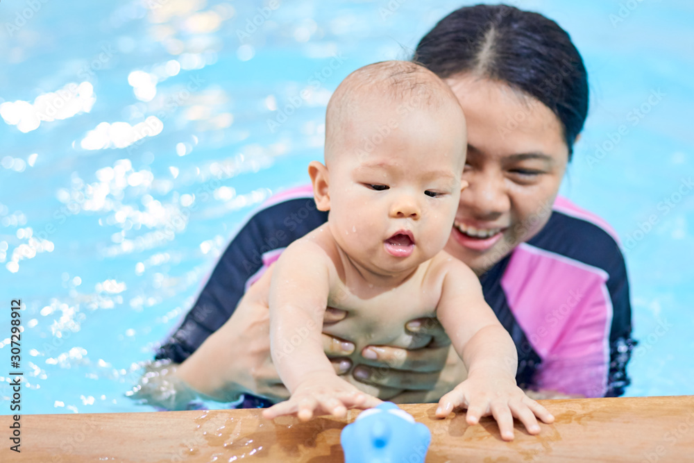 Cute little 6 months old Asian baby boy child try to grabbing a toy at