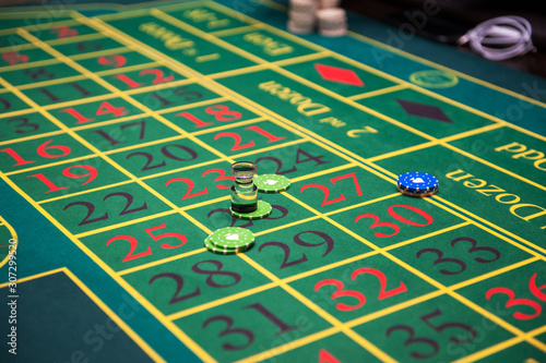 Casino, gambling and entertainment concept - green roulette table with colored chips ready to play