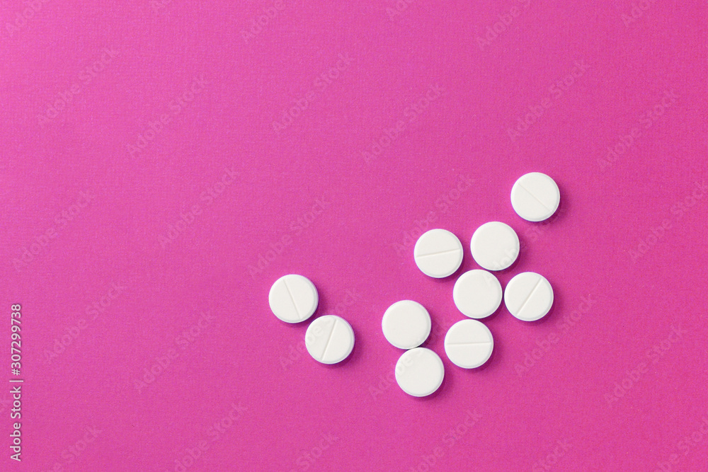 White round pills tablets on a bright pink background close up. Top view, copy space. Medical concept White round pills tablets on a bright pink background close up. Top view, copy space. Medical concept