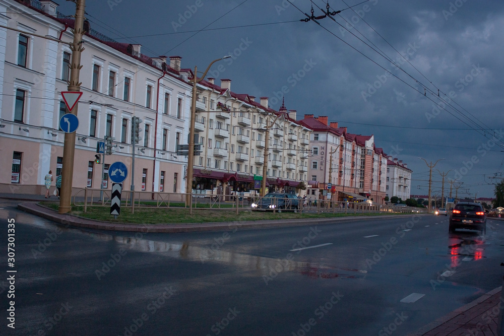 Sights and views of Grodno. City street after rain, evening, sky with storm clouds, city transport, passers-by.