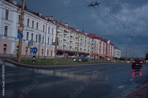 Sights and views of Grodno. City street after rain, evening, sky with storm clouds, city transport, passers-by.