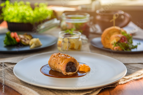 Different tasty dishes on the restaurant table, meat roll on the plate