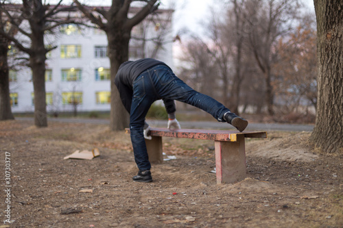 A young man does push ups on an iron park bench as he warms up for his daily workout or jogging