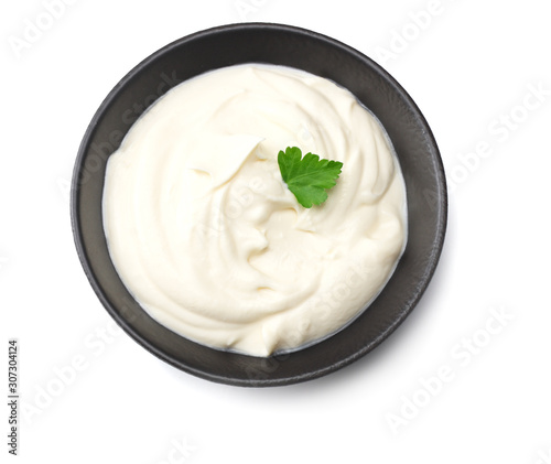 sour cream in black bowl isolated on white background. top view