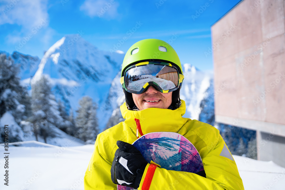 Photo of sportive man with snowboard against background of mountains Photo of sportive man with snowboard against background of mountains