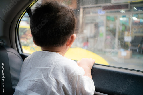 Toddler baby boy looking outside from car throught mirror