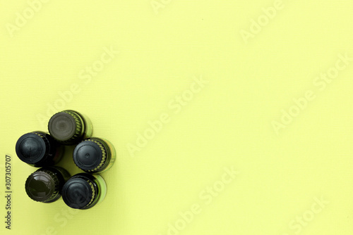 Brown bottles with essential oil on a yellow background. Flat lay, top view, copy space. Aromatherapy and spa concept