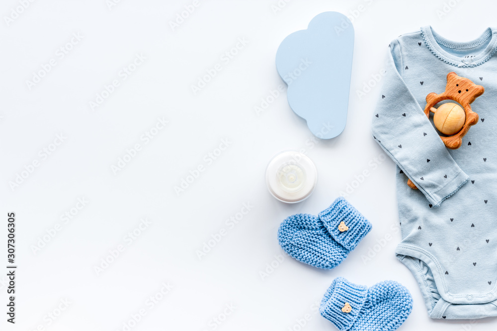 Newborn baby boy set - blue clothes as bodysuit, booties, toys - on white table top-down frame copy space - obrazy, fototapety, plakaty 