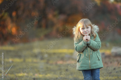 Only a preschool child in a jacket walks in a garden with falling leaves. © ElenaBatkova