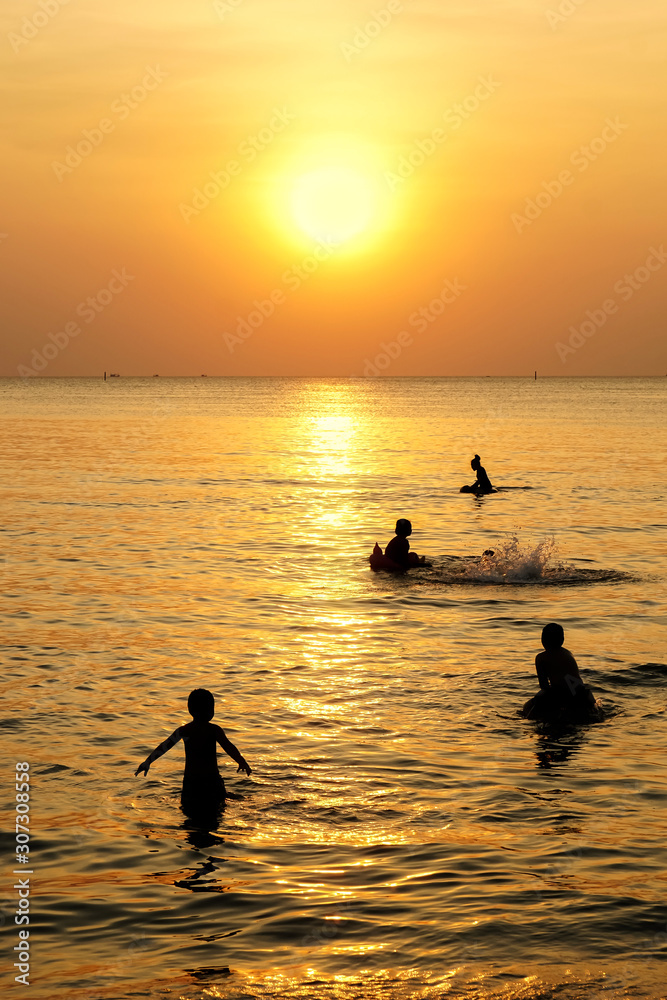 Silhouette children playing over yellow sunset beach