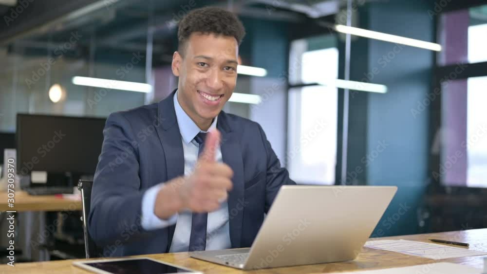 Ambitious Young Businessman doing Thumbs Up in Office Ambitious Young Businessman doing Thumbs Up in Office