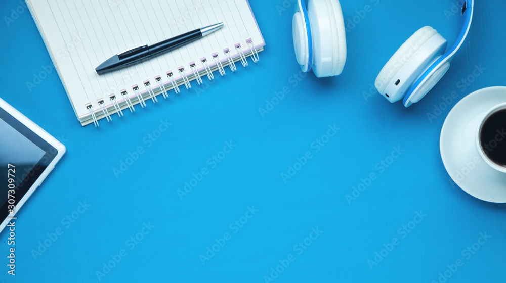 White wireless headphones, tablet, coffee on the blue background. White wireless headphones, tablet, coffee on the blue background.