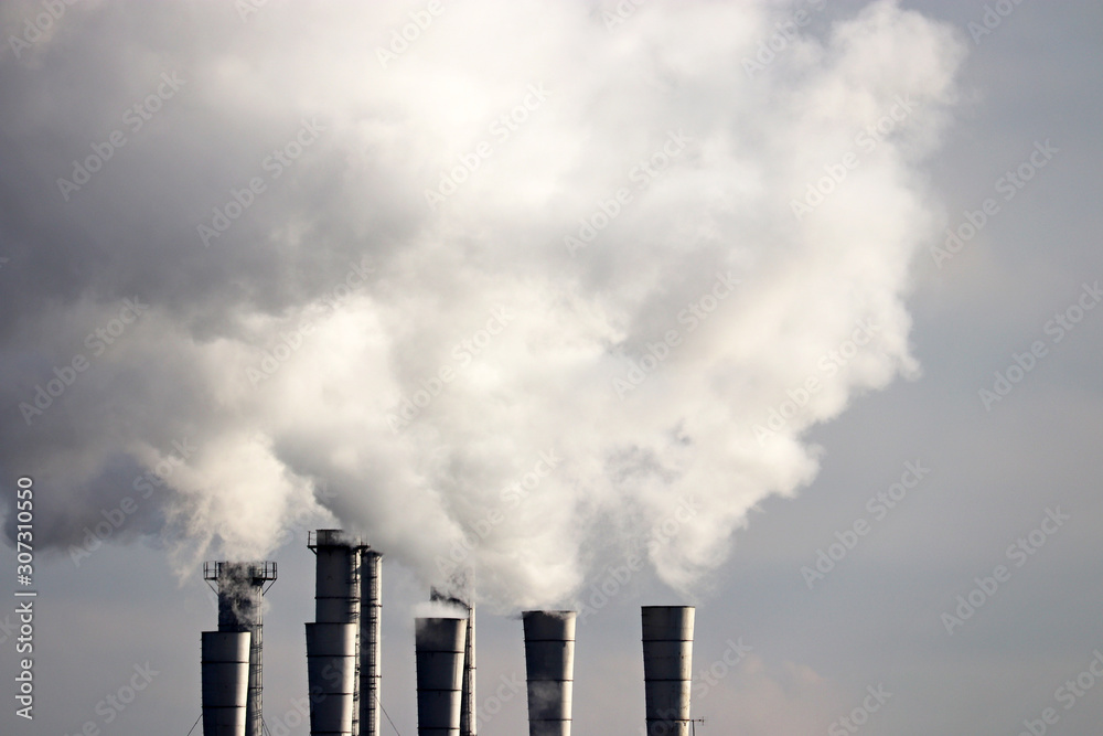 Smoke from the chimneys on dirty sky background, air pollution. Concept of industry and ecology, steam plant, heating season, global warming