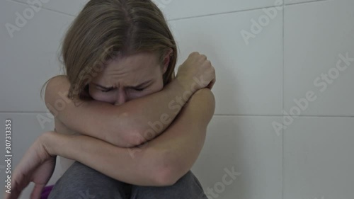 Woman with mental problem sufering for depression. Unhappy girl sitting at home bathroom with sad face expression. photo