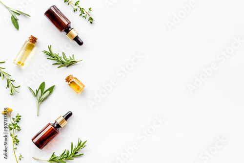 Essential oils and fresh herbs on white background top view pattern frame copy spacee photo