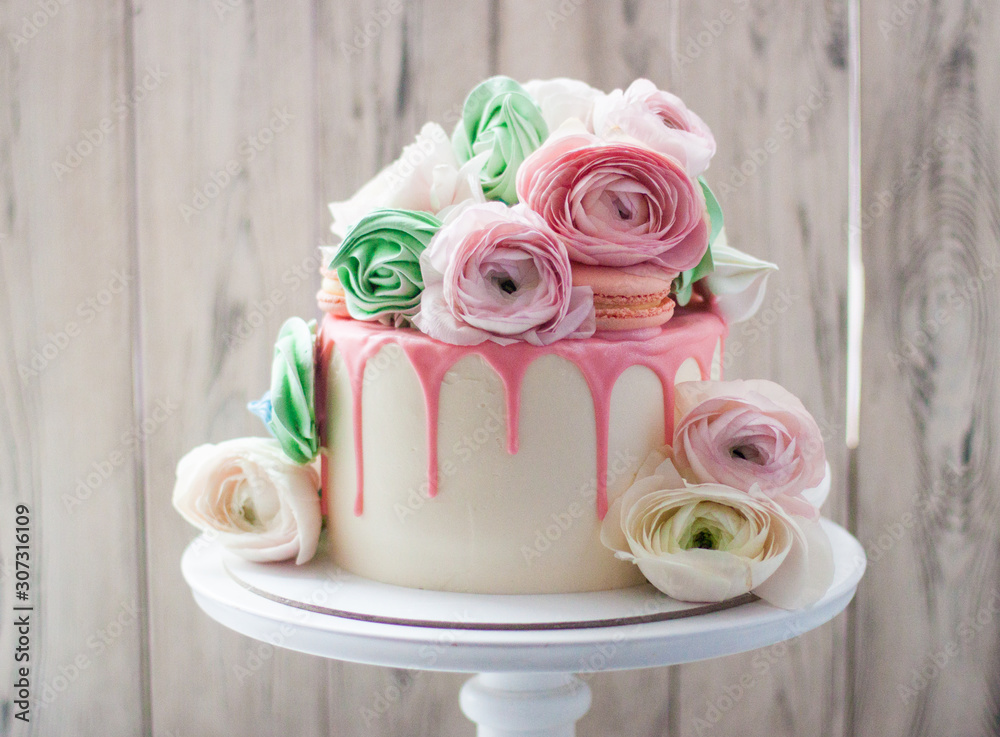 White cake with pink melted chocolate decorated with fresh flowers, roses, ranunculuses, macaroons and meringue swirls. White cake with pink melted chocolate decorated with fresh flowers, roses, ranunculuses, macaroons and meringue swirls.