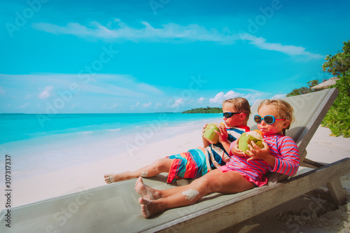 little boy and girl drinking coconut on beach