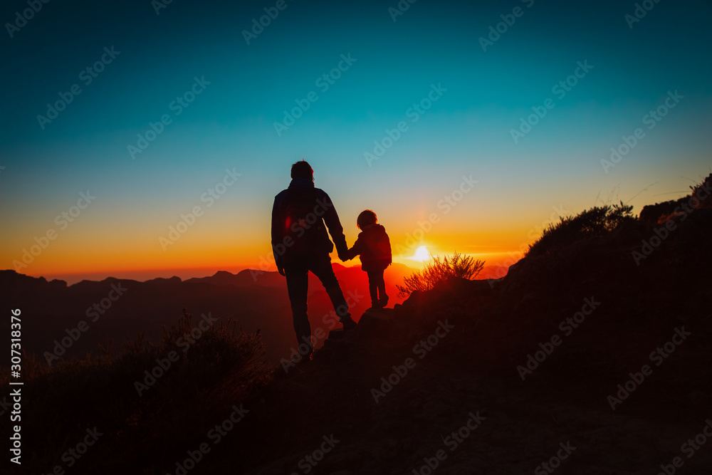 father and little daughter travel in mountains at sunset