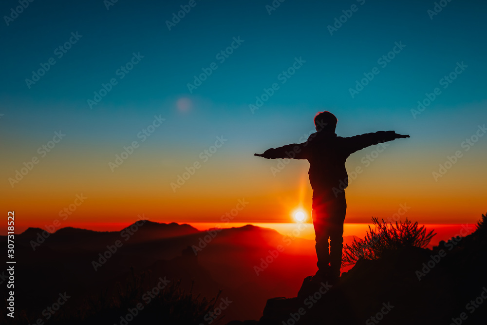 Silhouettes of happy boy enjoy travel at sunset mountains