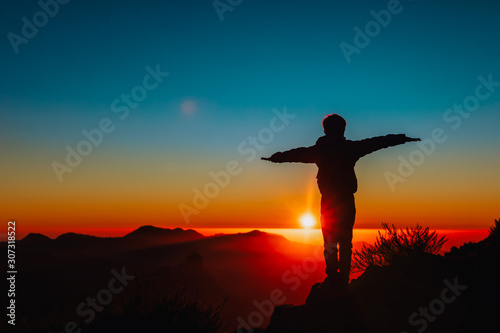 Silhouettes of happy boy enjoy travel at sunset mountains