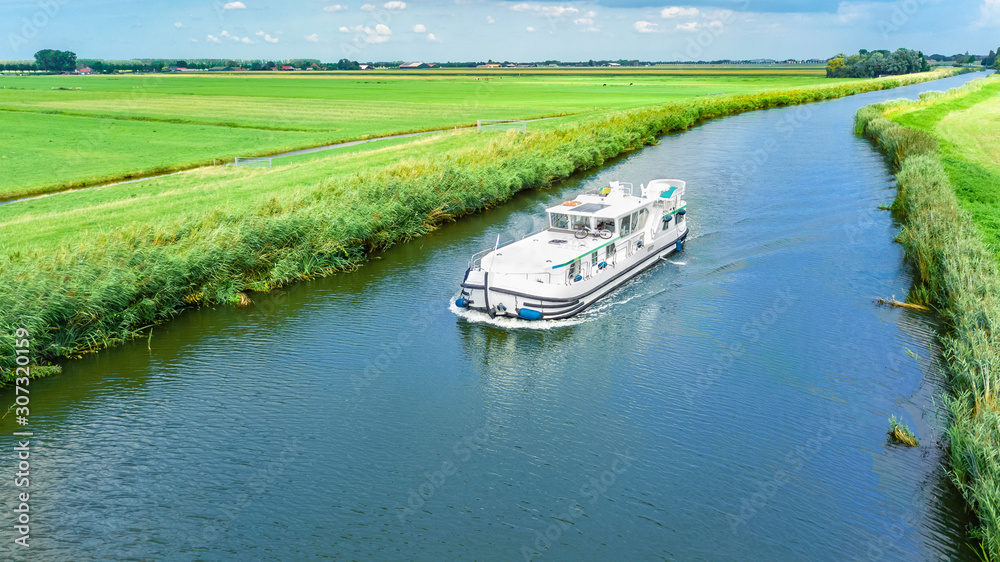 Aerial drone view of houseboat in canal and country landscape of Holland from above, family travel by barge boat and vacation in Netherlands