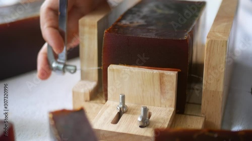 Selective focus of a bar / piece of homemade soap being picked up after the loaf of soap was cut by a single wire soap cutter