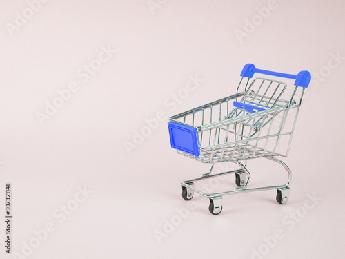 Small shopping cart on blue background. Space for text