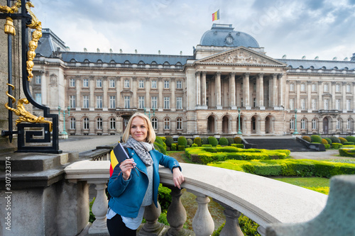 Woman with the flag of Belgium stands against the backdrop of the Royal Palace in Brussels, Belgium