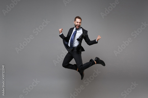 Fotografia Joyful young business man in classic black suit shirt tie posing isolated on grey background